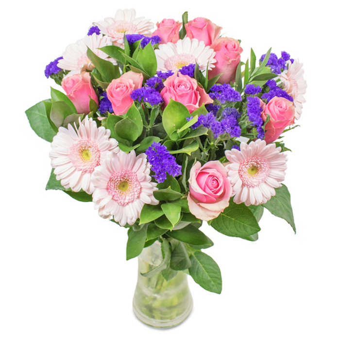 A captivating arrangement displayed in a clear glass vase, this South Wimbledon-inspired bouquet features a medley of approximately 7 to 9 expertly selected soft and medium pink roses-some gently unfurling, others still shyly closed, revealing spiral-shaped layers. These roses are harmoniously teamed with 5 to 7 pale pink gerbera daisies, their generous, sun-like heads forming an engaging focal point. Throughout the bouquet, vivid purple statice or limonium clusters add an energetic contrast, their hue deep and distinctive against the gentle spectrum of pinks. Lush, deep green leaves provide a flourishing backdrop, reminiscent of the verdant spaces that define the South Wimbledon area. The stems, visible through the pure glass vase, nestle in crystal-clear water, signifying freshness and the attentive work that Florist South Wimbledon brings to each order. The bouquet's versatile elegance makes it a fitting tribute for birthdays, anniversaries, Mother's Day, or as an uplifting decorative touch for either home or office. Every blossom is placed with precision, mirroring the neighbourhood's love for tradition and lively community spirit, and designed to convey warmth, celebration, and genuine affection.
